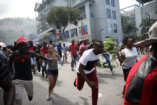 Protesters run away as Haitian National Police officers disperse them with tear gas during a march in Port-au-Prince, Haiti on October 17, 2018. (Photo by Andres Martinez Casares/Reuters)