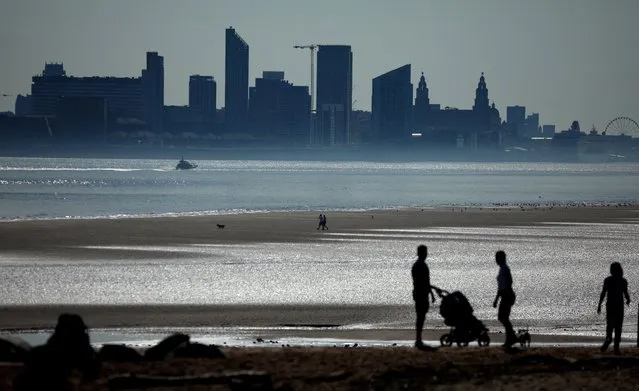 People walk on the beach in front of the skyline of Liverpool on the banks of the River Mersey in Wallasey, Britain on September 3, 2023. (Photo by Phil Noble/Reuters)