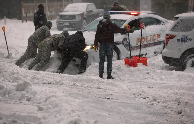 National Guard members and other people help to push a police car, which got stuck in the snow on January 23, 2016 in Washington, DC. Heavy snow continued to fall in the Mid-Atlantic region causing “life-threatening blizzard conditions” and affecting millions of people. (Photo by Alex Wong/Getty Images)