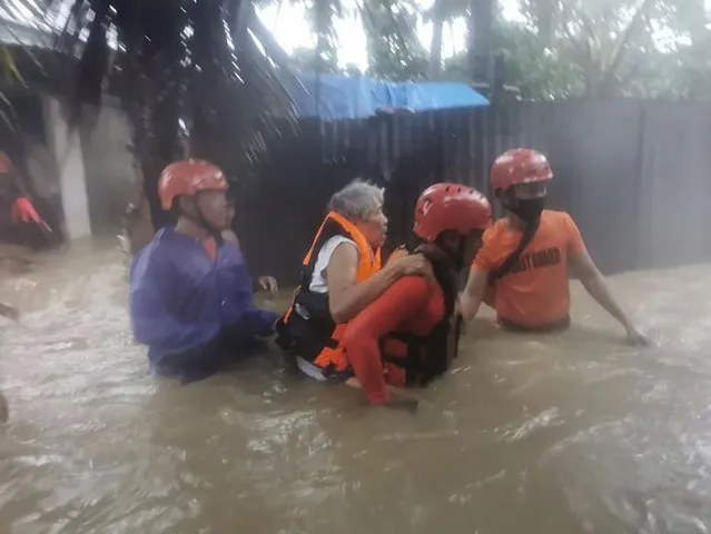 In this photo provided by the Philippine Coast Guard, rescuers evacuate residents to safer ground as floods caused by Tropical Storm Choi-wan hits Maasin City in Southern Leyte province, central Philippines on Tuesday June 1, 2021. The tropical storm has left at least a few people dead and displaced hundreds of villagers in the southern and central Philippines, where it set off flooding and landslides, officials said Wednesday. (Photo by Philippine Coast Guard via AP Photo)