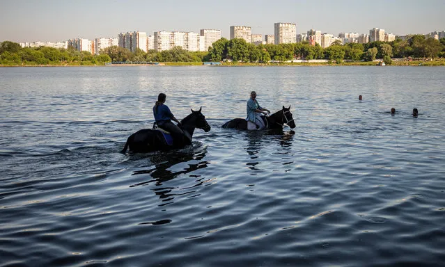 Women cool their horses off in the water at Borisovskye Ponds in Moscow on June 20, 2021, as temperatures have reached 30 degrees Celsius. (Photo by Dimitar Dilkoff/AFP Photo)