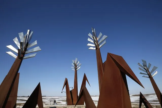 A couple walks past a metal sculpture representing a corn field in Marion, Iowa, March 8, 2015. (Photo by Jim Young/Reuters)