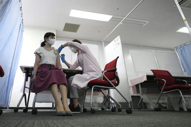 In this June 14, 2021, file photo, a flight attendant of Japan Airlines takes Moderna's COVID-19 vaccine shot at their office in Haneda Airport as the airline company began its workplace vaccination, in Tokyo. After months of delays due to political and bureaucratic bungling as well as a shortage of vaccines, inoculations in Japan are taking off, and the drive is now racing down to the wire with the Olympics starting in one month. (Photo by Eugene Hoshiko/AP Photo/File)