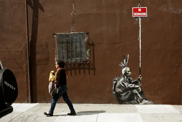 A woman walks past a drawing, believed to be the work of elusive British street artist Banksy, in the Mission District of San Francisco, May 4, 2010. (Photo by Robert Galbraith/Reuters)