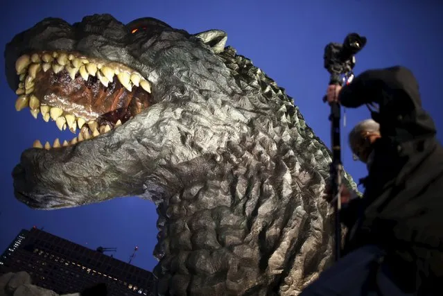A real-scale head of Godzilla is displayed at the balcony of the newly-built commercial complex as a new Tokyo landmark while a photographer tries to take photos during its unveiling at Kabukicho shopping and amusement district in Tokyo April 9, 2015. (Photo by Issei Kato/Reuters)