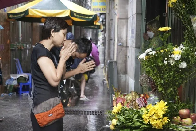 People pray in front of a make shift shrine set up in front of a building that was caught on fire in Hanoi, Vietnam Thursday, September 14, 2023. A fire broke just before midnight Tuesday in the apartment building that killed scores of people. (Photo by Hau Dinh/AP Photo)