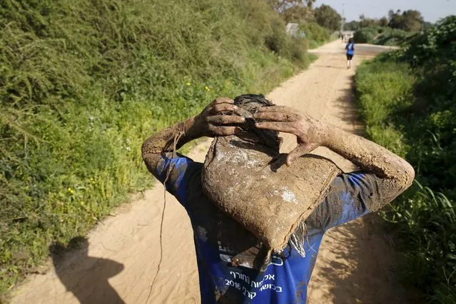 An Israeli teenager runs with a sandbag as he participates in an annual combat fitness training competition, as part of his preparations ahead of his compulsory army service, near Kibbutz Yakum, central Israel February 19, 2016. (Photo by Baz Ratner/Reuters)