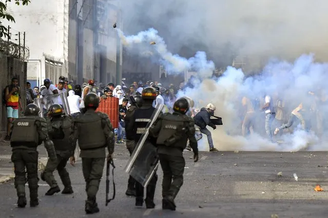 Opposition demonstrators clash with security forces during a protest against the government of President Nicolas Maduro on the anniversary of the 1958 uprising that overthrew the military dictatorship, in Caracas on January 23, 2019. Venezuela's National Assembly head Juan Guaido declared himself the country's “acting president” on Wednesday during a mass opposition rally against leader Nicolas Maduro. (Photo by Yuri Cortez/AFP Photo)