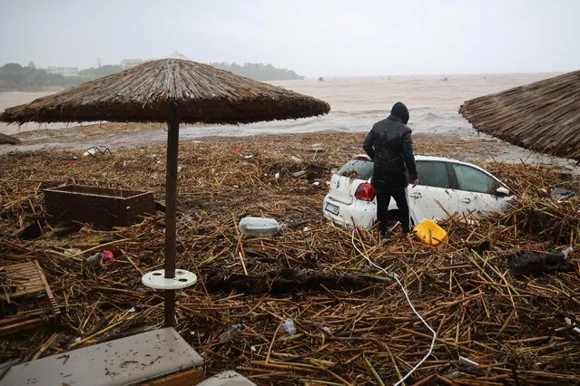 A man looks at a vehicle on the beach of the popular resort of Agia Pelagia, on the southern Greek island of Crete, following flash floods on October 15, 2022. (Photo by Costas Metaxakis/AFP Photo)