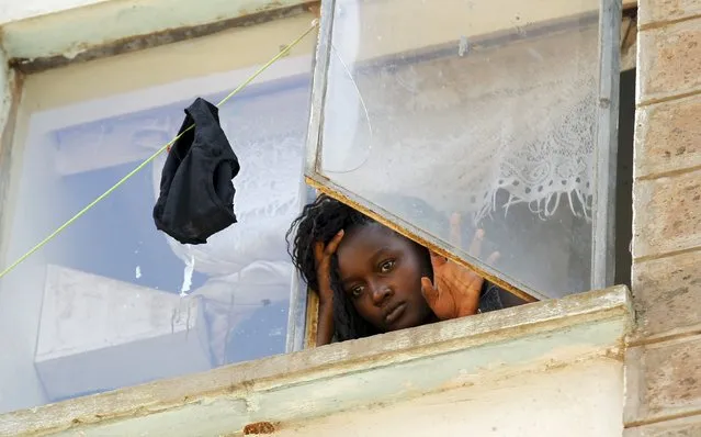 A student at the University of Nairobi looks down from the window at the Kimberly ladies hostels at the Kikuyu campus near the capital Nairobi, April 12, 2015. A Kenyan student died and more than 100 others were injured as they fled after a electricity transformer explosion before dawn on Sunday triggered fears that their campus was being attacked, officials said. (Photo by Thomas Mukoya/Reuters)