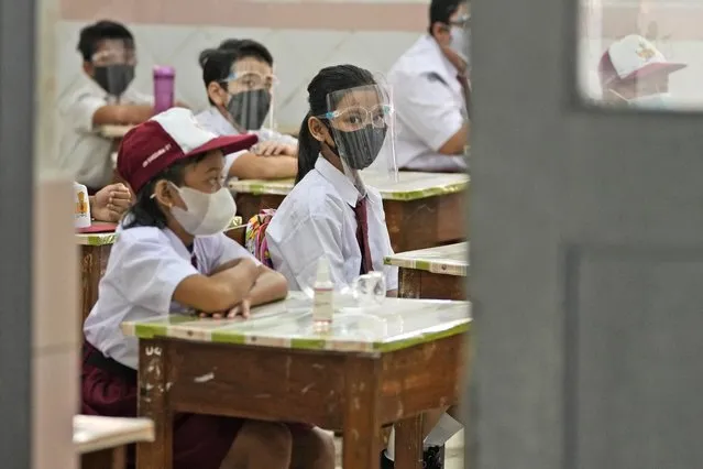Students wearing face masks to help prevent the spread of COVID-19 attend class during the first day of school reopening at an elementary school in Jakarta, Indonesia, Monday, August 30, 2021. (Photo by Dita Alangkara/AP Photo)