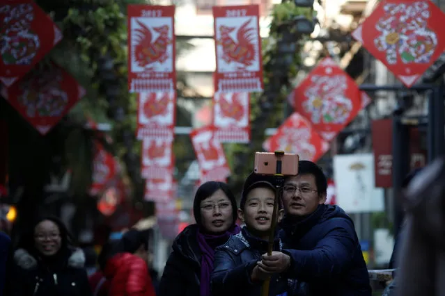 A family takes a selfie in front of decorations placed to celebrate the upcoming Chinese New Year of Rooster at a shopping area in Shanghai, China January 23, 2017. (Photo by Aly Song/Reuters)