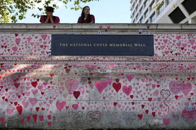 Nurses from the nearby hospital rest atop the National Covid Memory Wall in London, Thursday, September 16, 2021. Although the number of people now contracting COVID-19 is way higher than this time last year – over 30,000 new infections a day – the British government has opted not to re-introduce further virus restrictions for England, as the vaccine drive this year has reduced the number of people requiring treatment for COVID-19 and subsequently dying. (Photo by Frank Augstein/AP Photo)