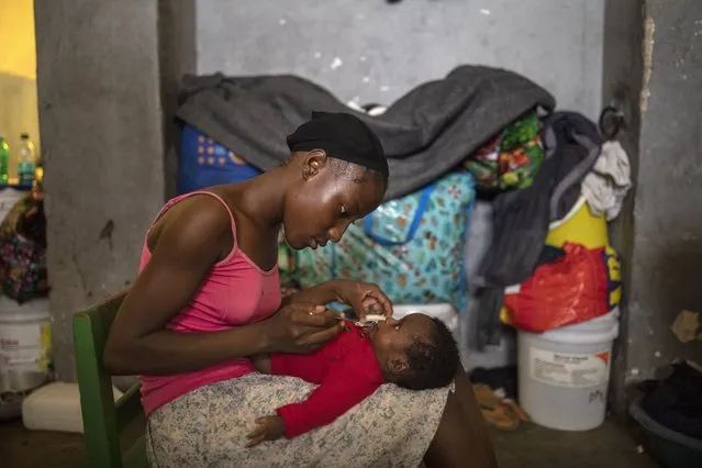A woman feeds her infant son in a shelter for internally displaced people due to violence, at a school converted into a shelter, in Port-au-Prince, Haiti, Tuesday, September 14, 2021. Officials say the gangs' fight over territory in Port-au-Prince has forced hundreds of families to abandon burned or ransacked homes in impoverished communities, with many of them staying in gymnasiums and other temporary shelters that are running out of water, food and items like blankets and clothes. (Photo by Rodrigo Abd/AP Photo)