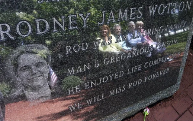 In this Tuesday, September 11, 2012 file photo, Pat Wotton, left, is reflected in a memorial to her husband Rodney James Wotton, as she sits with Dorothy Greene, second left, Jean Wotton, Rodney's mother, and Eunice Saporito, right, in Middletown, N.J. The marker for Rodney Wotton is one of 37 in the Middletown World Trade Center Memorial Gardens for those from the town in central New Jersey, who died in the attack on the World Trade Center in 2001. (Photo by Mel Evans/AP Photo/File)