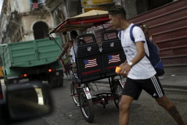 A man walks past a tricylce adorned with stickers in the U.S. colors in Havana, March 17, 2016. (Photo by Ueslei Marcelino/Reuters)