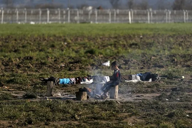 A boy sits next to a fire at a makeshift camp for refugees and migrants at the Greek-Macedonian border near the village of Idomeni, Greece, March 19, 2016. (Photo by Alkis Konstantinidis/Reuters)