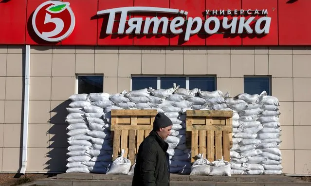A man walks by a fortified Pyaterochka supermarket, in the course of the Russia-Ukraine conflict in the town of Shebekino in the Belgorod region, Russia, on March 11, 2024. (Photo by Maxim Shemetov/Reuters)