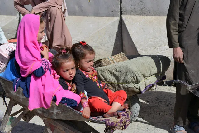 Children sit on a wheelbarrow while waiting with relatives to cross into Pakistan at the Afghanistan-Pakistan border crossing point in Spin Boldak on November 3, 2021, after authorities reopened the border following nearly a month-long closure. (Photo by Javed Tanveer/AFP Photo)