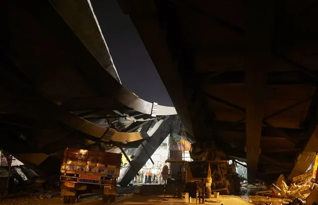 Vehicles are parked under the wreckage of a collapsed flyover as rescue efforts continue in the Indian city of Kolkata on March 31, 2016. Hundreds of emergency workers in India battled March 31 to rescue dozens of people still trapped after a flyover collapsed onto a busy street, killing at least 20 people and injuring nearly 100. (Photo by Dibyangshu Sarkar/AFP Photo)