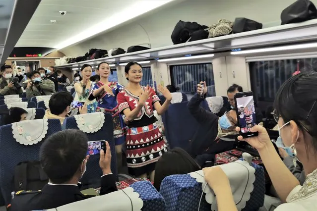 Women in ethnic dresses perform on a passenger carriage of the first regular train service on the Chinese section of the railway between Kunming and Vientiane, the Laotian capital, after its debut ceremony in Kunming in southwestern China's Yunnan province, Friday, December 3, 2021. The railway is one of hundreds of projects under Beijing's Belt and Road Initiative to build ports, railways and other facilities across Asia, Africa and the Pacific. (Photo by Chinatopix via AP Photo)