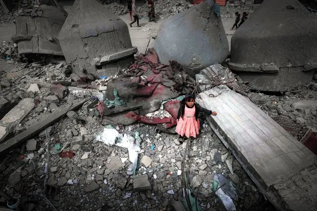 A Palestinian girl wearing a pink dress stands amidst the ruins of the Al-Faruq Mosque that was destroyed during Israeli bombardment, in Rafah on the southern Gaza Strip on March 22, 2024, amid ongoing battles between Israel and the militant group Hamas (Photo by Mohammed Abed/AFP Photo)