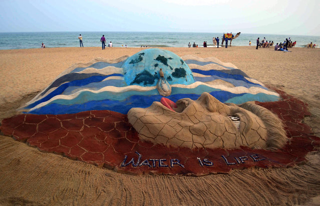 Visitors are seen near a sand sculpture created by sand artist Sudarshan Pattnaik on the eve of World Water Day, at the Bay of Bengal's eastern coast beach at Puri, some 65 kms from Bhubaneswar, India, 21 March 2014. World Water Day is celebrated around the globe on 22 March as a means of focusing attention on the importance of freshwater and advocating for the sustainable management of freshwater resources. (Photo by EPA/STR)