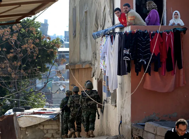 A Lebanese family watches Lebanese army soldiers as they take their positions after clashes erupted between supporters and opponents of Syrian President Bashar Assad, near the Sunni neighborhood of Tariq Jadideh, in Beirut, Lebanon, Sunday, March 23, 2014. (Photo by Hussein Malla/AP Photo)
