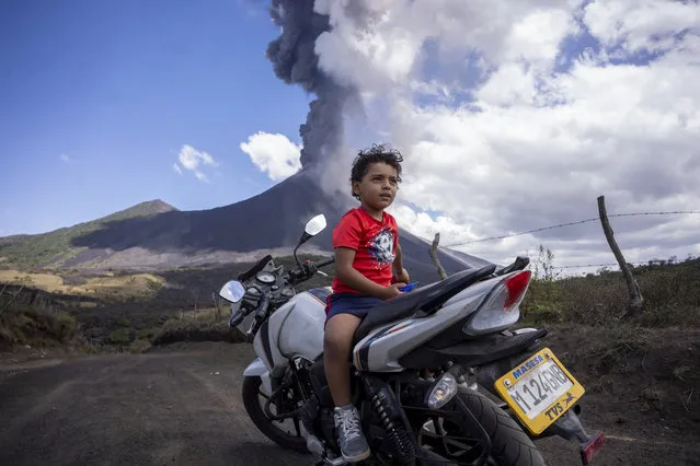 A child sits on a motorcycle as the Pacaya volcano erupts in the background, viewed from San Vicente Pacaya, Guatemala, Wednesday, March 3, 2021. (Photo by Santiago Billy/AP Photo)