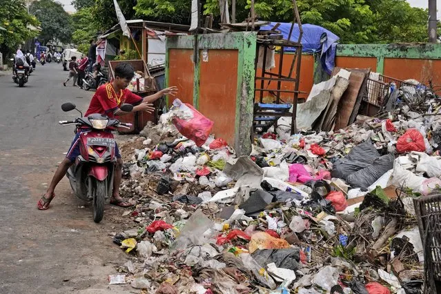 A man throws adds a bag of waste to an open garbage dump in Jakarta, Indonesia, Tuesday, January 25, 2022. (Photo by Dita Alangkara/AP Photo)