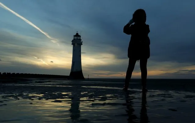 A woman takes photographs of the newly illuminated Perch Rock lighthouse in New Brighton, northern England April 23, 2016. (Photo by Phil Noble/Reuters)