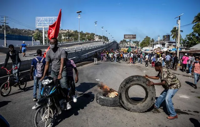 Factory workers demanding a salary increase, protest in Port-au-Prince, Haiti, on February 16, 2022. Workers employed in factories that produce textiles and other goods say they earn 500 gourdes ($5) per day for nine hours of work and require a minimum of 1,500 gourdes ($15) per day. (Photo by Richard Pierrin/AFP Photo)