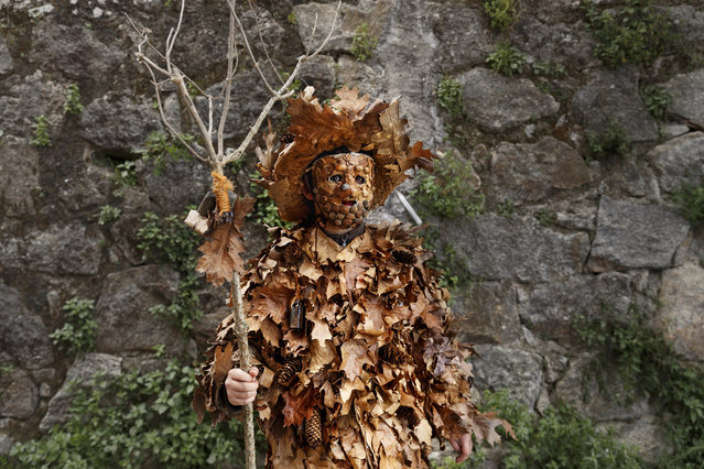 In this April 1, 2017 picture a man dressed as a “Trapajon” and representing a natural entity poses for a picture before a traditional Spanish mask gathering in the small village of Casavieja, Spain. Every spring they come from towns across central and northwestern Spain, clad in elaborate costumes – some as trees, others as bears, still others as monsters who could have emerged from some sort of fever dream. First they attend local festivals, often timed to coincide with celebrations of spring. They parade through narrow streets in masks with horns and manes, multicolored conical hats, sheepskins and cowbells. The festivals' origins are for the most part vague and their titles – such as the “Cucurrumachos” in Navalosa town or the “Zarramaches” in the village of Casavieja – more often than not untranslatable. Then, they converge on one town, a different one each year, for a special event to showcase characters from the various festivals. The idea is to promote the festivals to help keep the towns' cultural heritage alive. This year's event, celebrated April 1 in Casavieja, featured the comical hairy bear and “Trapajon” straw figures of “La Vijanera” festival and the “Harramacho”, savage-looking characters from the “Cucurrumachos” fiesta. (Photo by Daniel Ochoa de Olza/AP Photo)