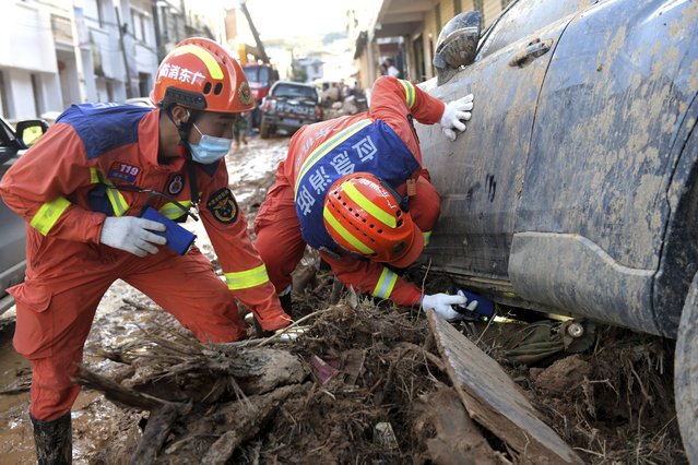 In this photo released by Xinhua News Agency, rescuers look under a vehicle in a flood-affected area in Sishui Township of Pingyuan County, Meizhou City, southern China's Guangdong Province, Thursday, June 20, 2024. Multiple people have died and several people were reported missing after downpours in recent days caused historic flooding in rural parts of Guangdong province in southern China, while authorities warned Friday of more flooding ahead in other parts of the country. (Photo by Lu Hanxin/Xinhua via AP Photo)