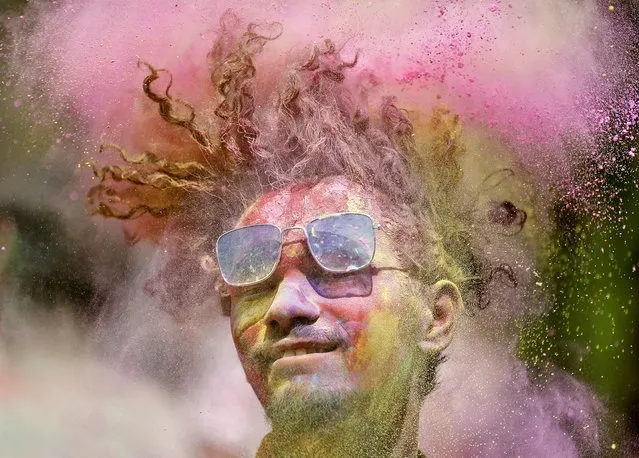 A man covered in coloured powder shakes his head during Holi celebrations in Ahmedabad, India, March 17, 2022. (Photo by Amit Dave/Reuters)