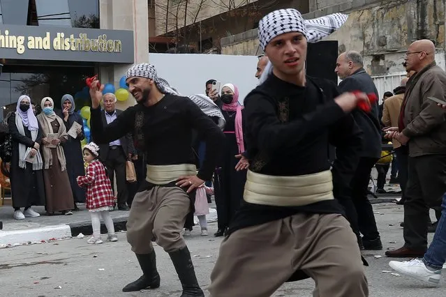Men wearing traditional costumes perform Dabke, a Levantine folk dance seen at joyous occasions, in front of the Samir Mansour Bookstore that was destroyed during Israel's war with Gaza's Hamas rulers last May, during the re-opening ceremony in Gaza City, Thursday, February 17, 2022. (Photo by Adel Hana/AP Photo)