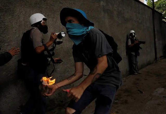 A demonstrator prpeares to throw a molotov cocktail during clashes with riot police while rallying against Venezuela's President Nicolas Maduro in Caracas, Venezuela May 1, 2017. (Photo by Carlos Garcia Rawlins/Reuters)