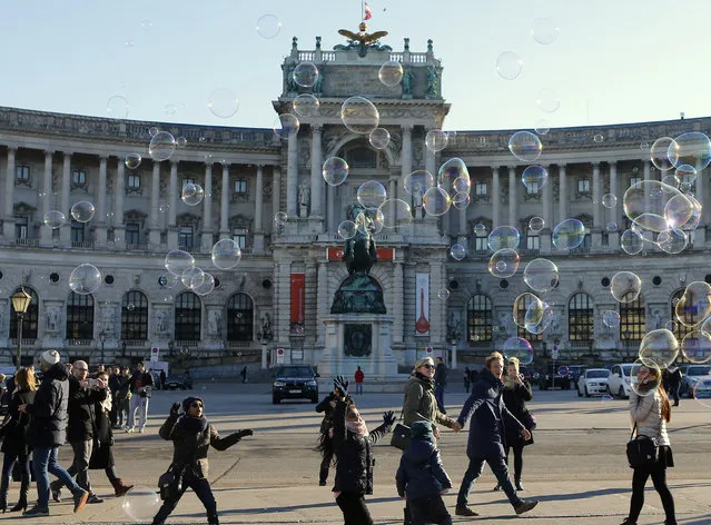 Children try to catch soap bubbles in front of Hofburg palace on a sunny winter day in Vienna, Austria, December 23, 2015. (Photo by Heinz-Peter Bader/Reuters)