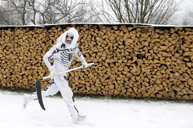 A reveler depicting a grim reaper runs during a traditional St Nicholas procession in the village of Valasska Polanka, Czech Republic, Saturday, December 7, 2019. This pre-Christmas tradition has survived for centuries in a few villages in the eastern part of the country. The whole group parades through village for the weekend, going from door to door. St.Nicholas presents the kids with sweets. The devils wearing home made masks of sheep skin and the white creatures representing death with scythes frighten them. (Photo by Petr David Josek/AP Photo)