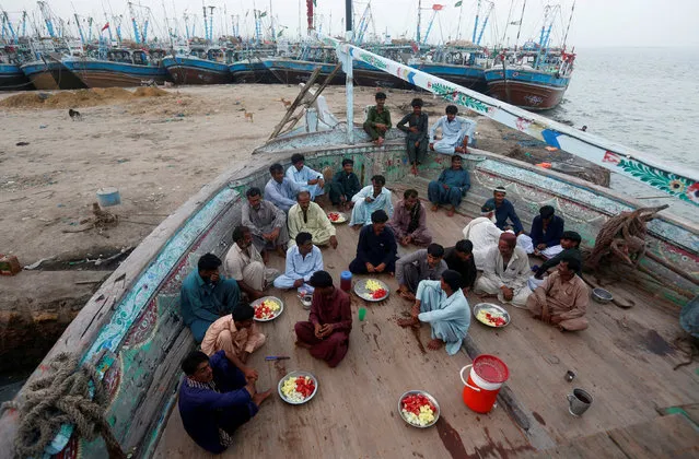 Fishermen sit on a fishing boat as they prepare to break their fast during a Muslim holy month of Ramadan in Ibrahim Hyderi, on the outskirts of Karachi, Pakistan June 1, 2017. (Photo by Akhtar Soomro/Reuters)