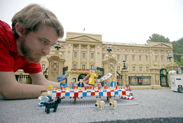 Legoland Windsor Resort model maker Guy Groom puts the finishing touches to a miniature street party outside a model of Buckingham Palace in Miniland ahead of the Patron's Lunch on The Mall to mark the Queen's official 90th birthday on June 12; Wednesday June 8, 2016. (Photo by Steve Parsons/PA Wire via AP Photo)