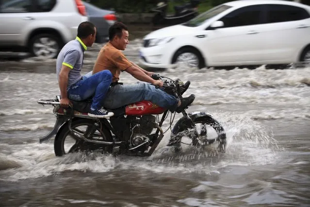 Motorists ride along a flooded street after a heavy rainfall in Jilin, Jilin province, June 28, 2014. (Photo by Reuters/Stringer)