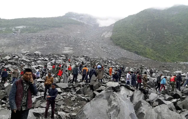Emergency personnel and locals work at the site of a landslide in Xinmo village in Maoxian County in southwestern China's Sichuan Province, Saturday, June 24, 2017. Dozens of people are feared buried by a landslide that unleashed huge rocks and a mass of earth that crashed into their homes in southwestern China early Saturday, a county government said. (Photo by Chinatopix via AP Photo)