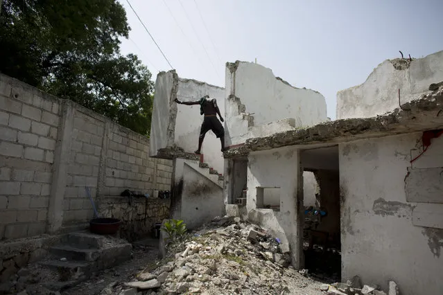 In this June 29, 2015 photo, a resident of the earthquake-damaged Hotel Le Palace makes his way downstairs from the room he inhabits in central Port-au-Prince, Haiti. Though much of the hotel was destroyed, some of the guest rooms, which still have intact walls, have become homes to people displaced by the quake. The ruined hotel has no running water or working sanitary facilities. (Photo by Rebecca Blackwell/AP Photo)