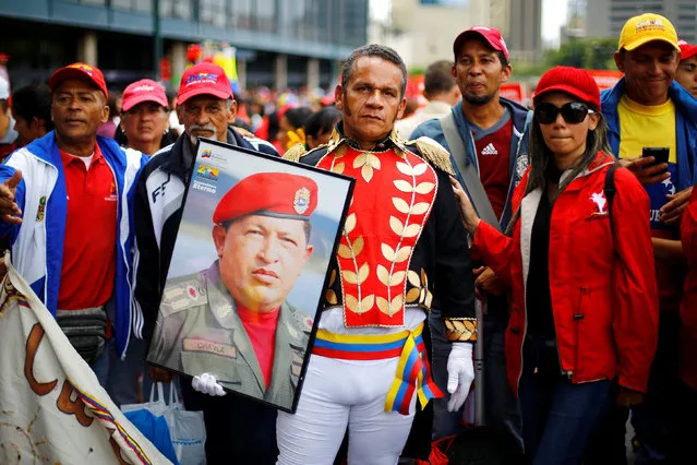 A man dressed as Venezuelan national independence hero Simon Bolivar, holds a picture of Venezuela's late President Hugo Chavez during a rally of members of the education sector in Caracas, Venezuela June 14, 2016. (Photo by Ivan Alvarado/Reuters)