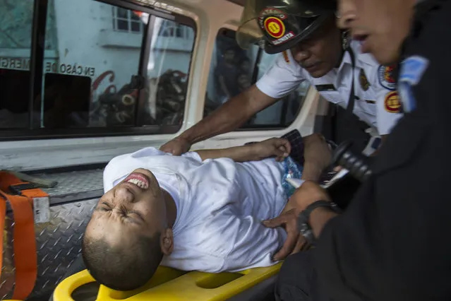 A juvenile inmate is attended by a medic and interrogated by a police officer, after he was injured during the recapture of the Juvenile Correctional Center Gaviotas by police, in Guatemala City, Monday, July 3, 2017. A riot at the center began when two inmates were found hanging in an apparent suicide, according to authorities. Apart from the two dead, 10 other inmates are reported to have escaped from the center. (Photo by Moises Castillo/AP Photo)