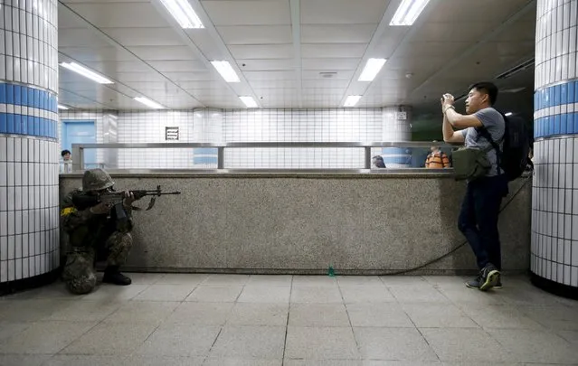 A South Korean soldier takes his position as a man takes photographs of him during an anti-terror drill in Seoul, South Korea, August 19, 2015. (Photo by Kim Hong-Ji/Reuters)