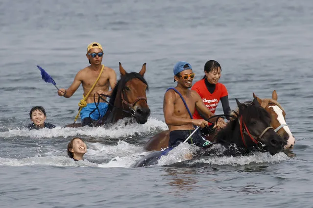Participants led by two horse trainers, wearing sunglasses, enjoy horse riding in the seashore of a Miura beach during a trekking tour by the Horse Trekking Farm Miurakaigan in Miura, south of Tokyo, Friday, August 25, 2017. (Photo by Shizuo Kambayashi/AP Photo)