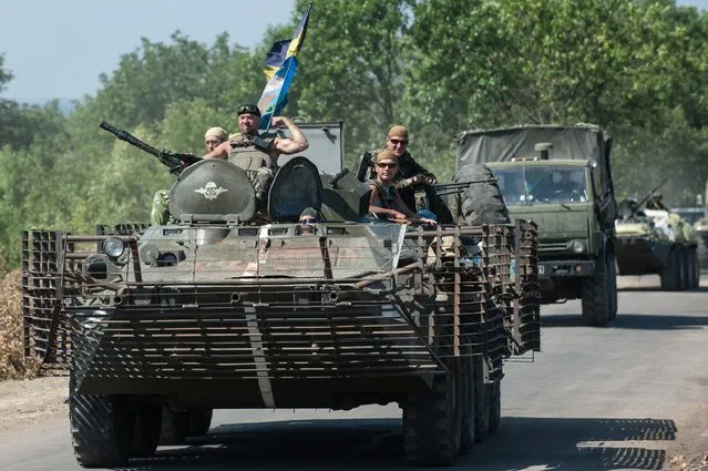 Ukrainian government troops roll on their military vehicles in Donetsk region, eastern Ukraine, Saturday, Aug. 9, 2014.  A top commander of the pro-Russia insurgency in eastern Ukraine said Saturday that Ukrainian forces have seized a key town, leaving the rebel region's largest city of Donetsk surrounded. (Photo by Alexander Zemlianichenko/AP Photo)