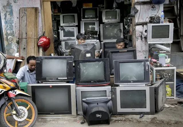 Technicians repair an old television (TV) at his stall at a slum area in Jakarta, Indonesia, Wednesday, May 25, 2016. (Photo by Tatan Syuflana/AP Photo)